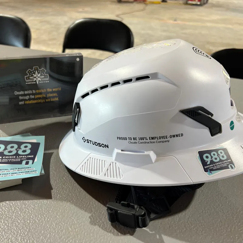Image of a safety helmet and stickers directing to the 988 Lifeline
